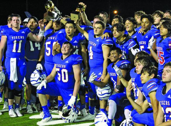 Sentinel photo/Mike Reddell Tidehaven Tigers celebrate after defeating the undefeated and 10th ranked 3A-2 team Odem Owls in the area playoff Saturday in Victoria. The players hoist the area and bi-district trophies they earned so far. 