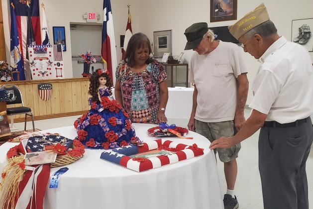Sentinel photo/MaLinda Reddell VFW Post 1428 member Ken Thames, right, gives Jeanne and Roland Fondon of Bay City a history Sunday, Aug. 14, of the Buddy Poppy and the exhibit that’s was on display at the post. 